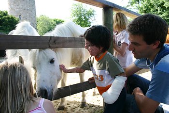 Ein Junge streichelt mit seiner verbrannten Hand ein Pferd. Psychosoziale Betreuung, ju care Kinderhilfe
